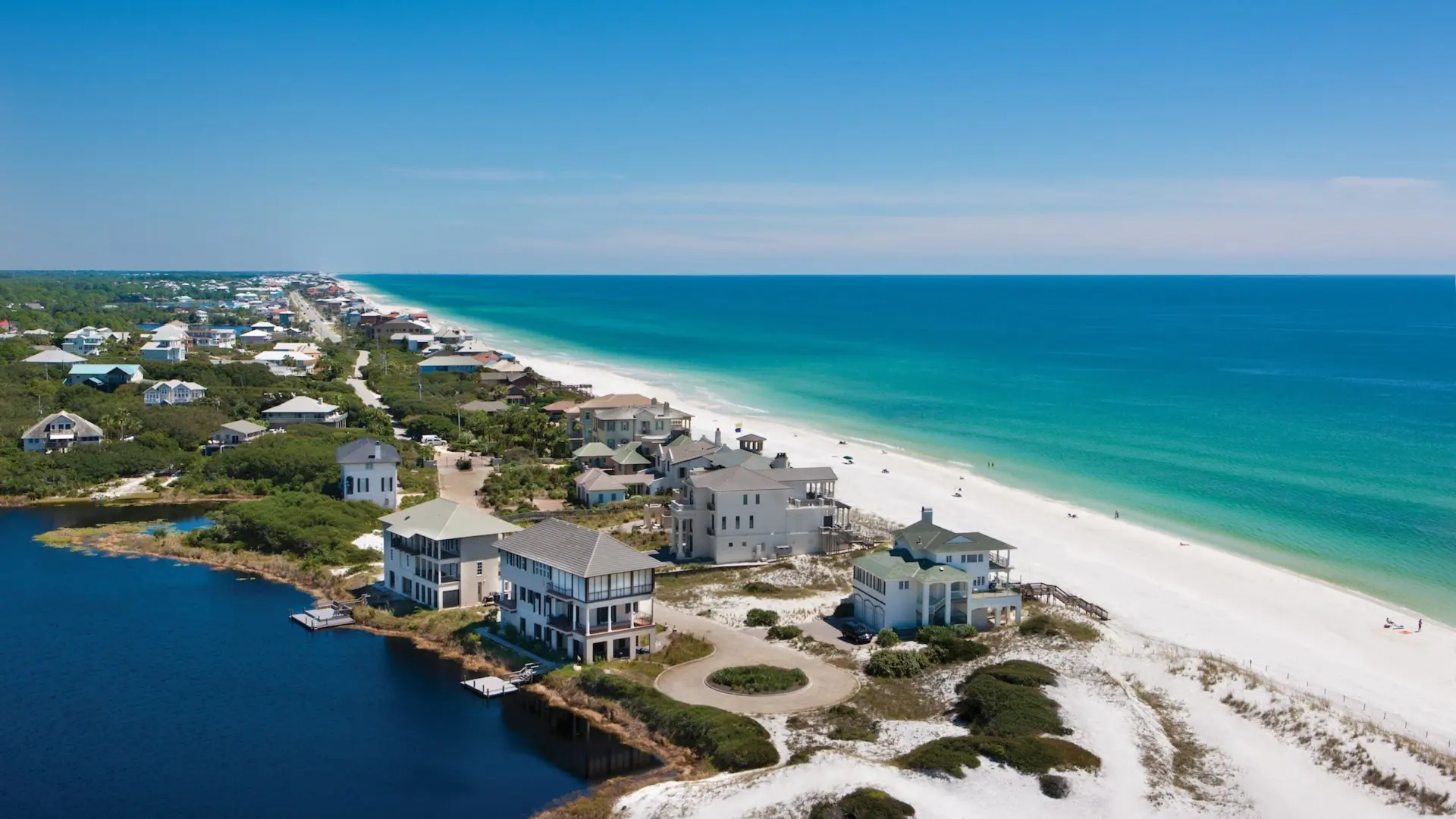 Aerial view of Santa Rosa Beach coastline with white sand, emerald Gulf water, and coastal homes along 30A, FL