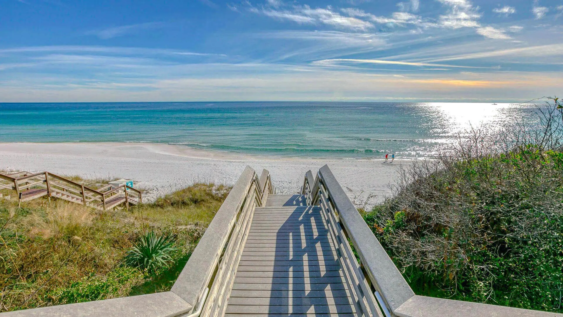 Wooden boardwalk over dunes leading to white sand beach and emerald Gulf water along Scenic 30A, FL